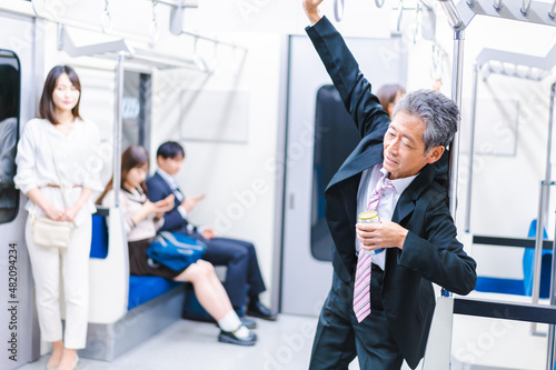 電車内で飲酒をする中年の男性