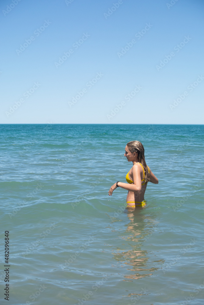 Fototapeta premium young girl laughing in a turquoise sea. upright photo. space for text. patagonia argentina