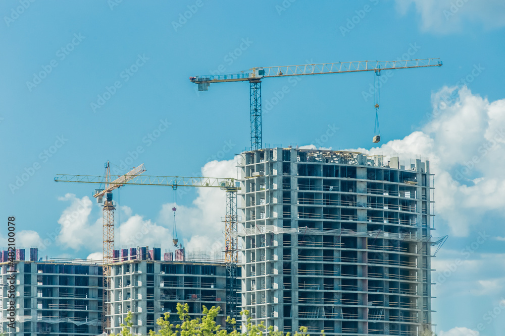 Tower crane, development of urban structures and construction of houses industry architecture on blue sky background