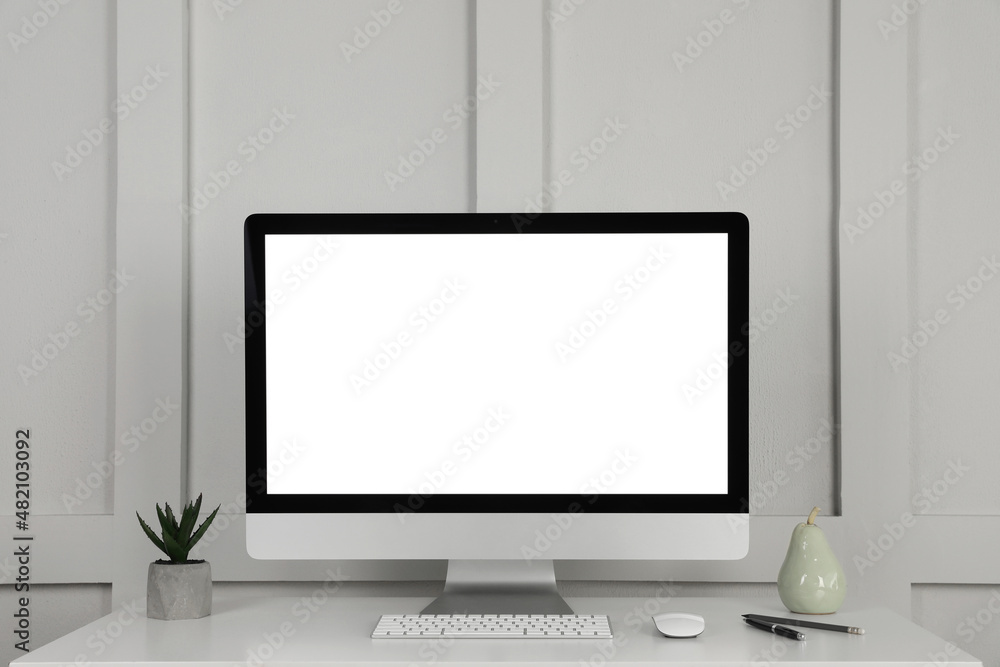 Fototapeta premium Modern computer, decor and office supplies on white wooden table near molding wall