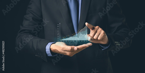 Businessman or trader is showing a growing virtual hologram stock, invest in trading.