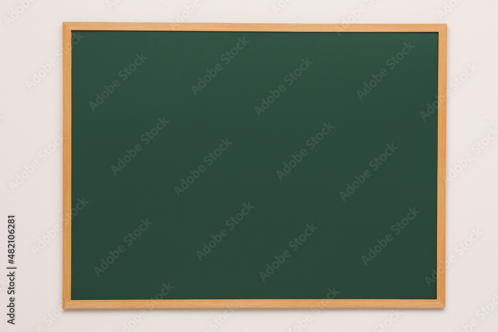 Clean green chalkboard hanging on grey wall Clean green chalkboard hanging on grey wall