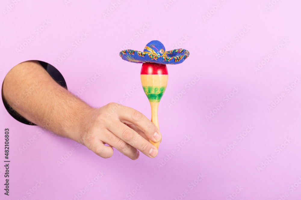 Cinco de mayo fiesta concept with hand holding a maraca with a sombrero on top. Symbols of Mexican celebration of national day