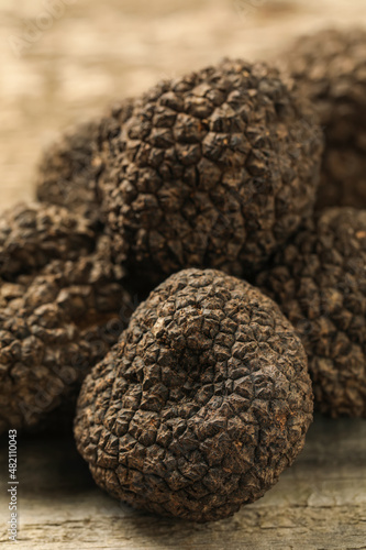 Heap of black truffles on wooden table, closeup