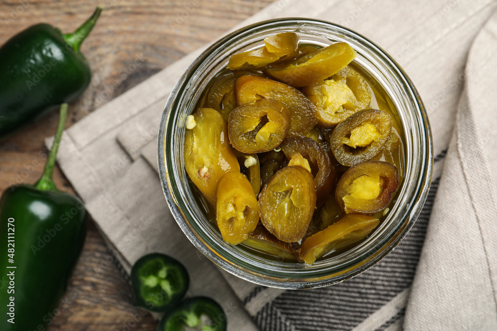 Fresh and pickled green jalapeno peppers on wooden table, flat lay Fresh and pickled green jalapeno peppers on wooden table, flat lay