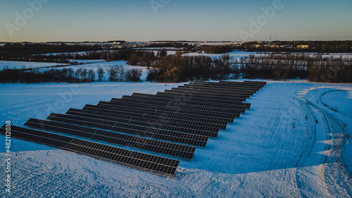 Solar panels in winter landscape as the sunsets off scene. Environmental protection and energy renewal.