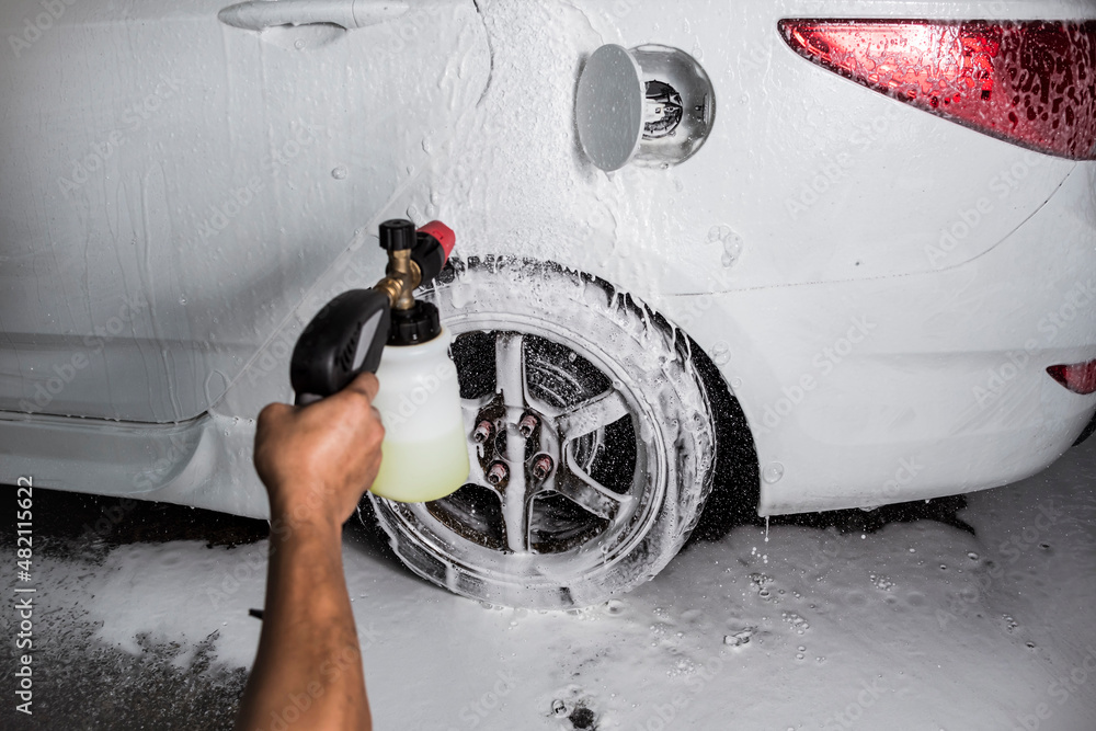 Blasting the rear of a white sedan with high-pressure shampoo. At a carwash  or auto detailing shop. Flash illuminated. Stock Photo | Adobe Stock
