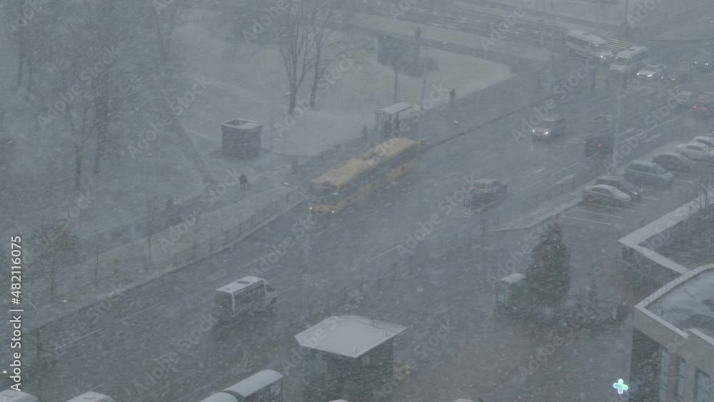 Top view of city street in heavy snowfall. Public transport, cars move ...