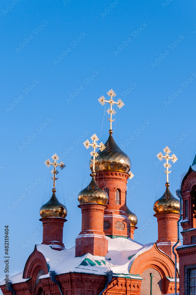 Domes with crosses of the Church of St. Innocent of Irkutsk in winter in the city of Khabarovsk against the blue sky