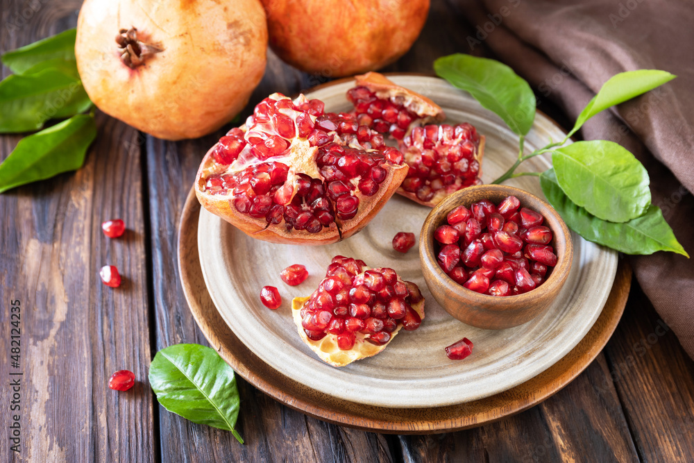 Ripe juicy pomegranate fruits in a wooden bowl on a rustic table. Diet and healthy food. Ripe juicy pomegranate fruits in a wooden bowl on a rustic table. Diet and healthy food.