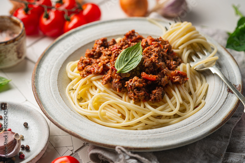 Tableau sur toile Pasta spaghetti bolognese with minced beef sauce, tomatoes, parmesan cheese and fresh basil in a plate on white tile background