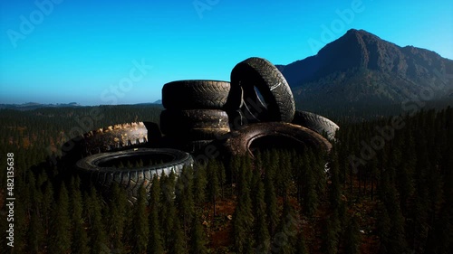 concept of environmental pollution with big old tires in mountain forest photo