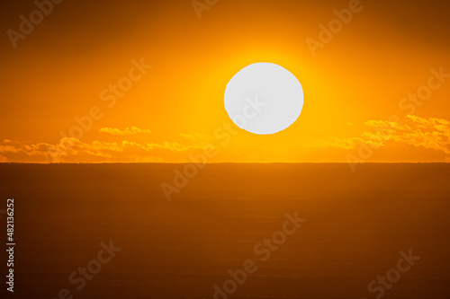 A large sun rises over the ocean at dawn during a heatwave. Australia.