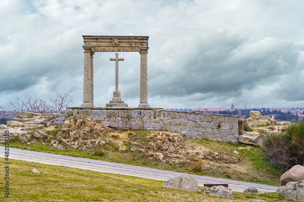 Stone cross on a hill overlooking the medieval city of Avila in Spain.