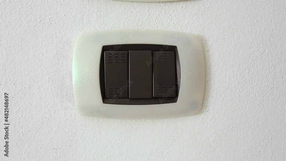 Female hand turning an electricity light switch on the wall Female hand turning an electricity light switch on the wall