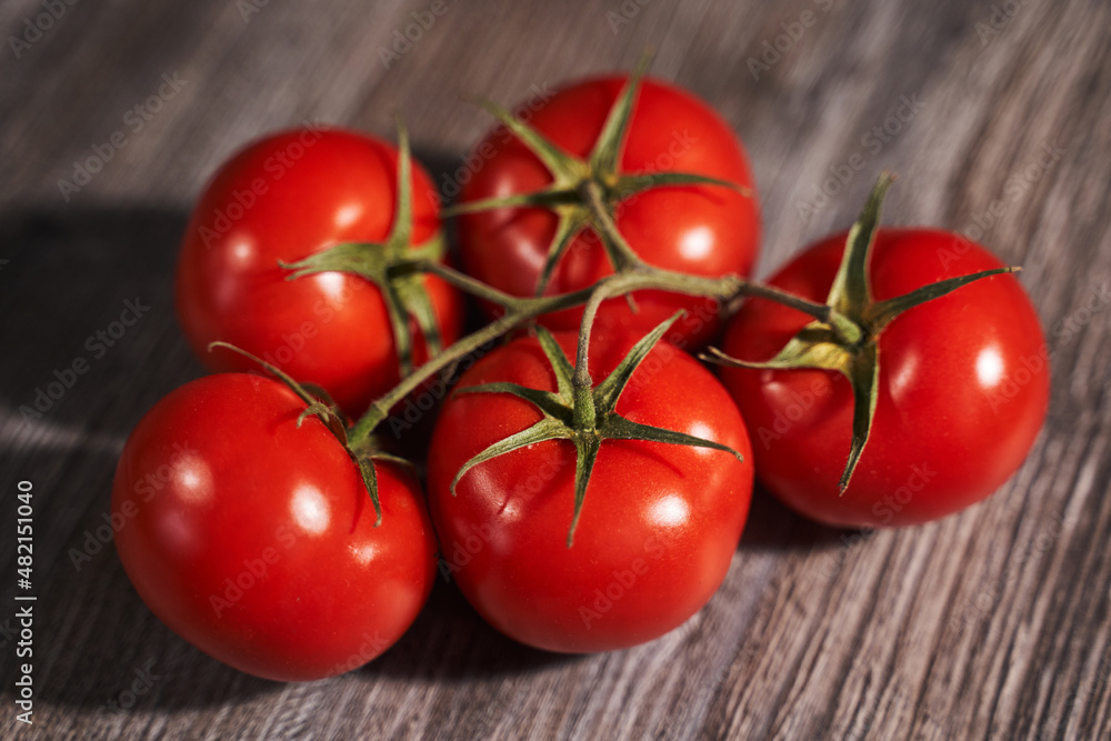 red tomatoes on a branch on a wooden background red tomatoes on a branch on a wooden background
