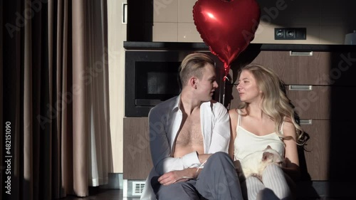 man and woman sit in the morning in the kitchen holding a heart-shaped balloon. concept for celebrating valentine's day, birthday, or anniversary.