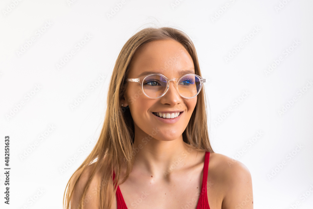 Smiling young woman in eyeglasses posing with crossed arms and looking at the camera over white background Smiling young woman in eyeglasses posing with crossed arms and looking at the camera over white background