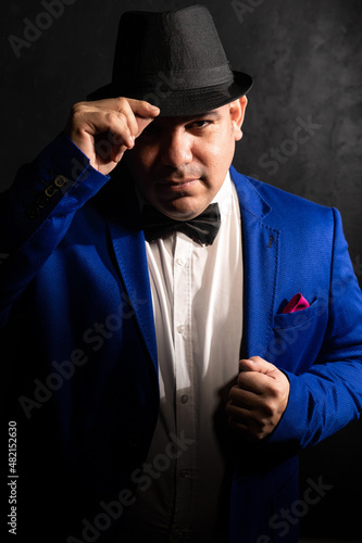 Portrait of latin american man in blue suit on a black background.
