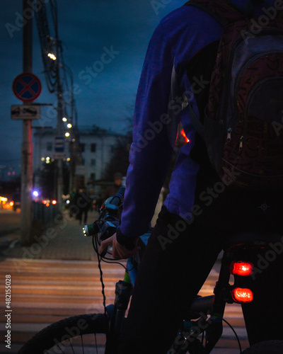 a closeup of a bicycle and a man in the crossing at the night