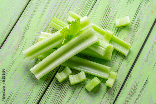 Pile of celery ribs on green wooden table. Healthy food background.