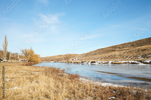 Beautiful natural landscape with birch and frozen river in winter.