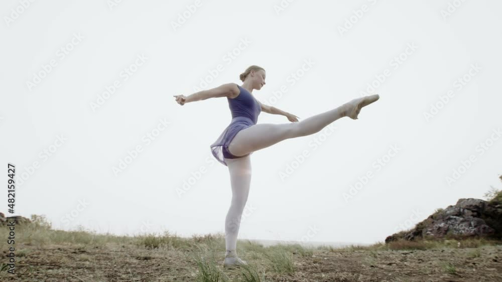 Dancer performs classical dance background sky, front view. Ballerina dances training movements in open air. Woman is engaged dancing Dancer performs classical dance background sky, front view. Ballerina dances training movements in open air. Woman is engaged dancing