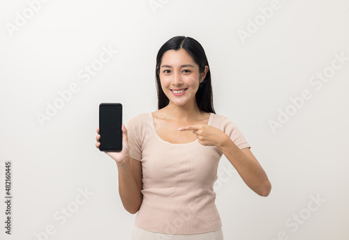 Pretty young asian woman using smartphone standing on isolated white background feeling happy. Shopping online payment with mobile phone. Excited and surprised female holding cellphone.