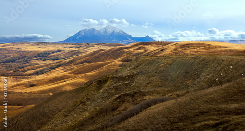 Laccoliths of the North Caucasus. Mountains of Caucasian mineral waters. Beautiful spring landscape with mountain peaks of magmatic origin, blue sky, clouds and sun. Beshtau Mountain.