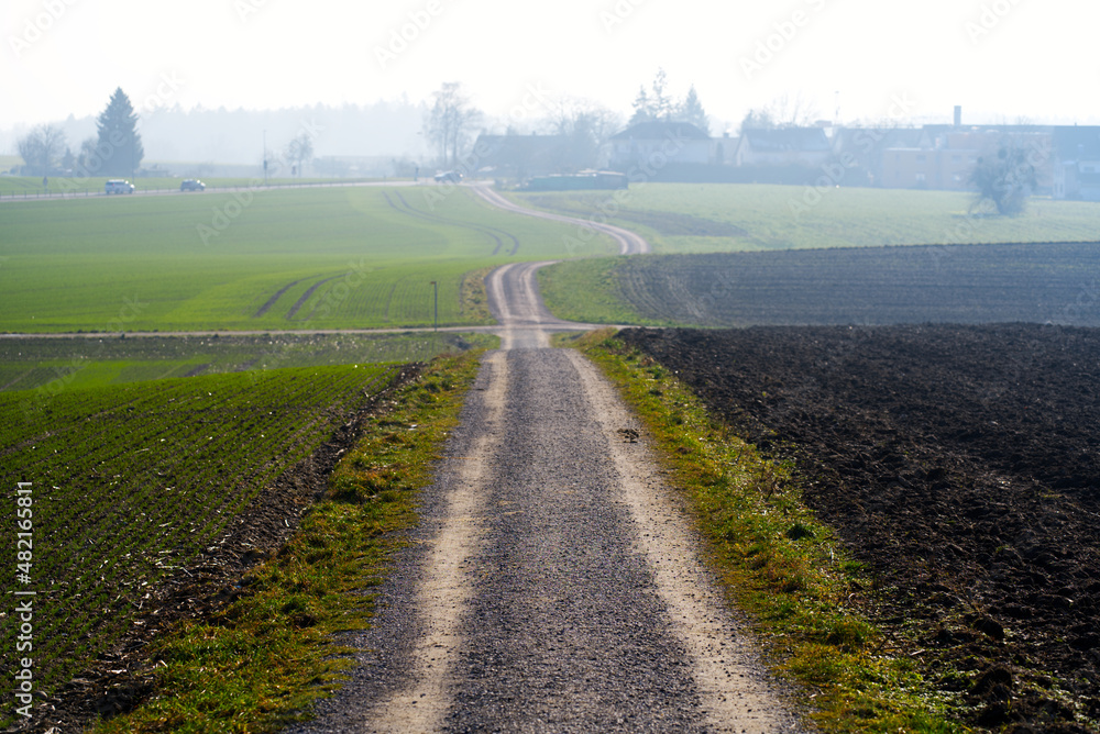 Rural gravel road with beautiful landscape on a sunny winter day near the airport. Photo taken January 13th, 2022, Zurich, Switzerland.