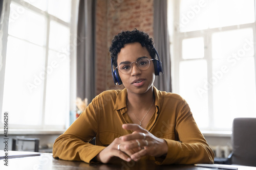 Confident African student, worker, intern in headphones head shot portrait. Friendly young Black woman talking online, having video conference, call, speaking, looking at camera. Video call screen photo