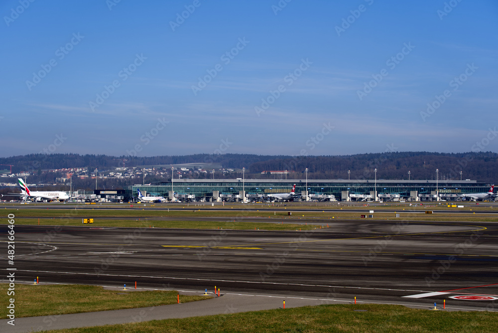 Terminal building named Dock Midfield with parked long distance airplanes on a sunny winter day. Photo taken January 13th, 2022, Zurich, Switzerland.