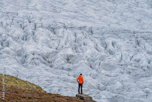 Unrecognizable tourist looking to a massive glacier