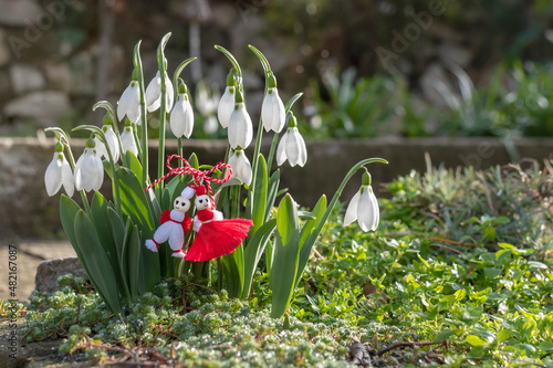 Spring background with white blossom snowdrops and martenitsa or martishor. Bulgarian symbol of spring, March 1 traditional trinket. Cheerful concept of beginning of spring photo