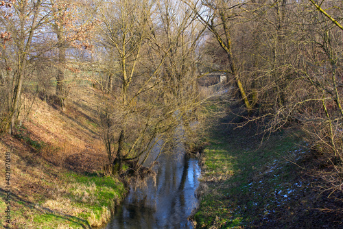 Little stream with beautiful reflections of trees on a sunny winter day. Photo taken January 13th, 2022, Zurich, Switzerland.