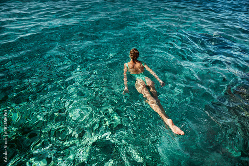 Top view swimming woman in green swimsuit bikini enjoying in blue sea water, tropical beach destination, inspiration travel vacation
