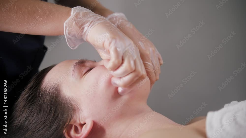 Massage session - young woman using her fingers on the face of her client Massage session - young woman using her fingers on the face of her client