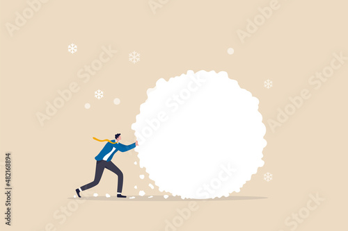 Obraz na plátně Snowball effect from small build up larger with potential risk, financial growth or mistake concept, businessman investor rolling large snowball build up from small getting bigger