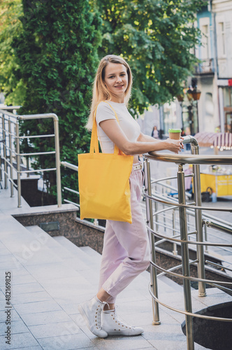 Young beautiful woman with linen eco bag on city background. © romaset