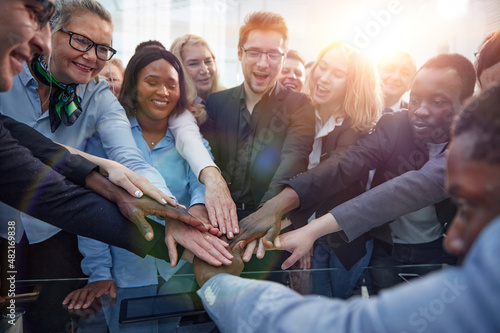 United coworkers standing with their hands together in modern of