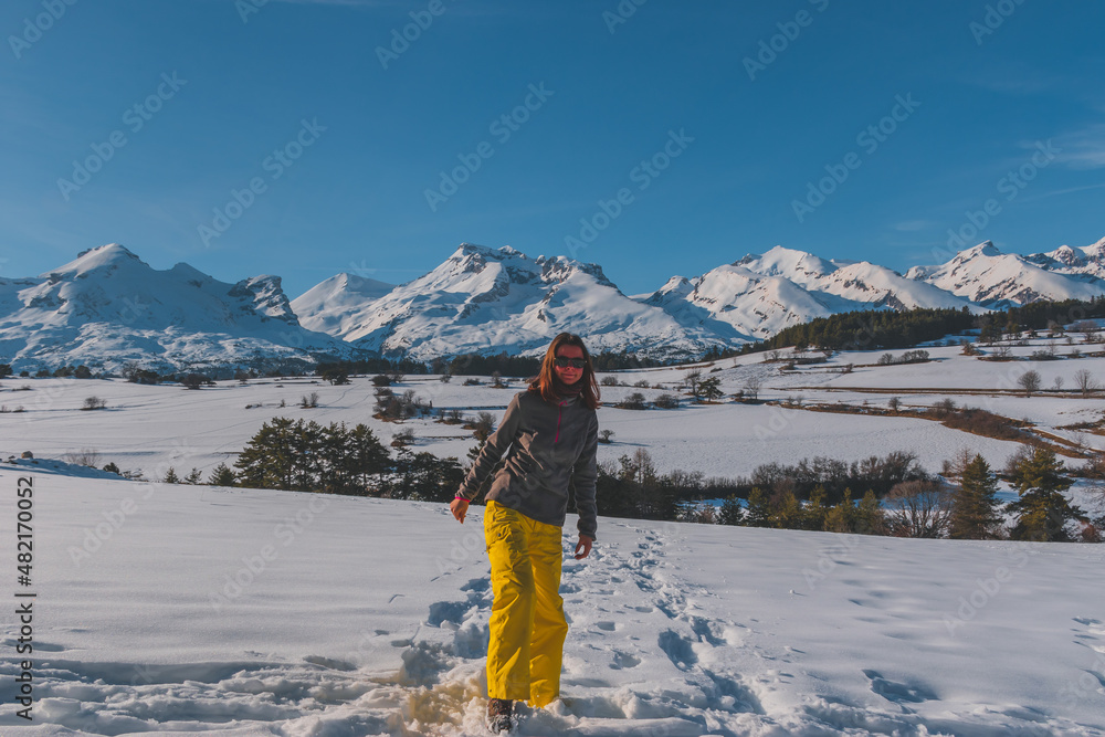 A full-body shot of a young Caucasian woman standing in the French Alps mountains (La Joue du Loup, Devoluy)