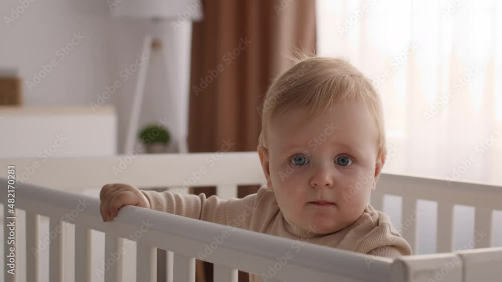 Portrait Of Cute Toddler Baby Standing In Wooden Crib At Home Portrait Of Cute Toddler Baby Standing In Wooden Crib At Home