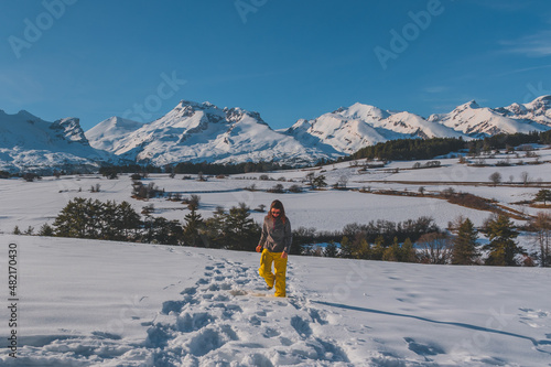 A full-body shot of a young Caucasian woman walking towards the camera in the French Alps mountains (La Joue du Loup, Devoluy) photo