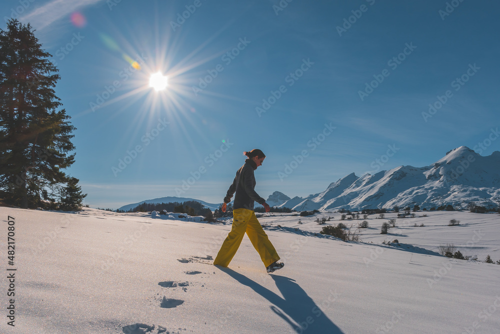 A full-body shot of a young Caucasian woman walking in the French Alps mountains (La Joue du Loup, Devoluy)