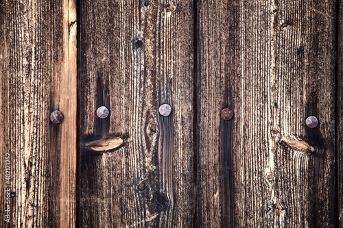 Dark wood boards texture close up. Vintage wooden surface with forged nails. Unpainted natural hardwood boards texture. Weathered surface of the old planks of wooden wall close-up. High contrast wood