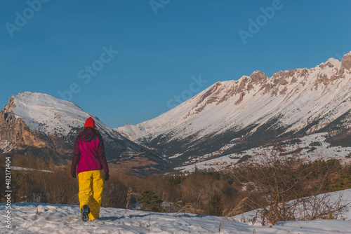A full-body shot of an unrecognizable young Caucasian woman walking in the French Alps mountains (La Joue du Loup, Devoluy)