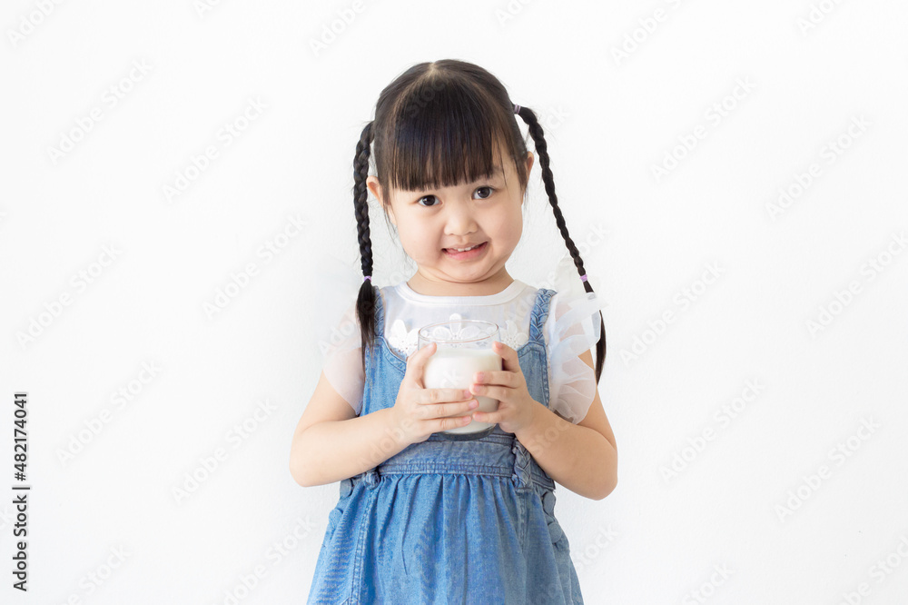 Portrait cute smiling Asian girl holding a glass of milk with white background.. Portrait cute smiling Asian girl holding a glass of milk with white background..