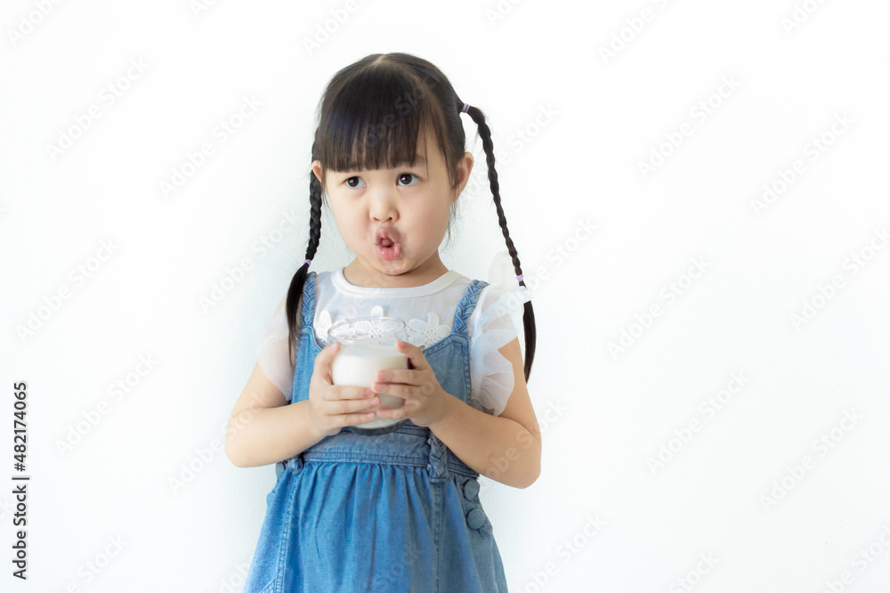 Portrait cute smiling Asian girl holding a glass of milk with white background.. Portrait cute smiling Asian girl holding a glass of milk with white background..