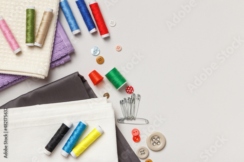 Sewing tools and accessories. Fabric and threads on a gray background. Top view flat lay copy space