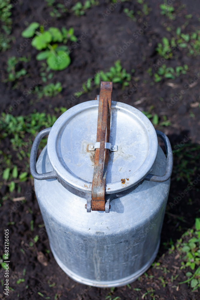 large vertical photo. summer time. aluminum jar in the middle of the garden. environmentally friendly materials on the farm. view from above. metal lock with a clip on the barrel. large vertical photo. summer time. aluminum jar in the middle of the garden. environmentally friendly materials on the farm. view from above. metal lock with a clip on the barrel.